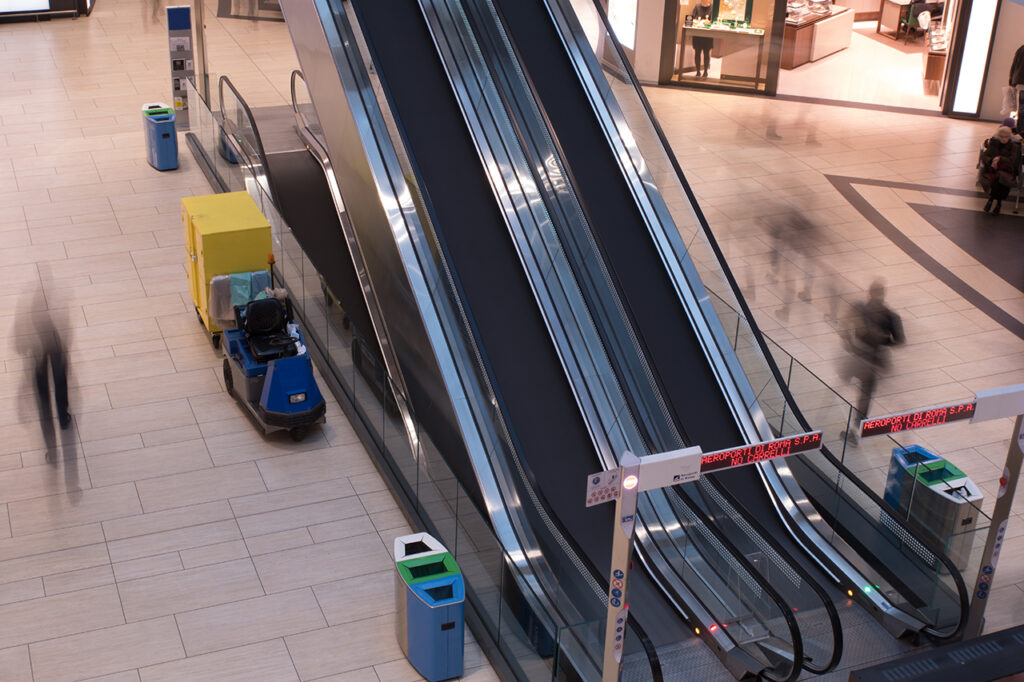 Escaleras mecánicas en aeropuerto con movimiento de personas